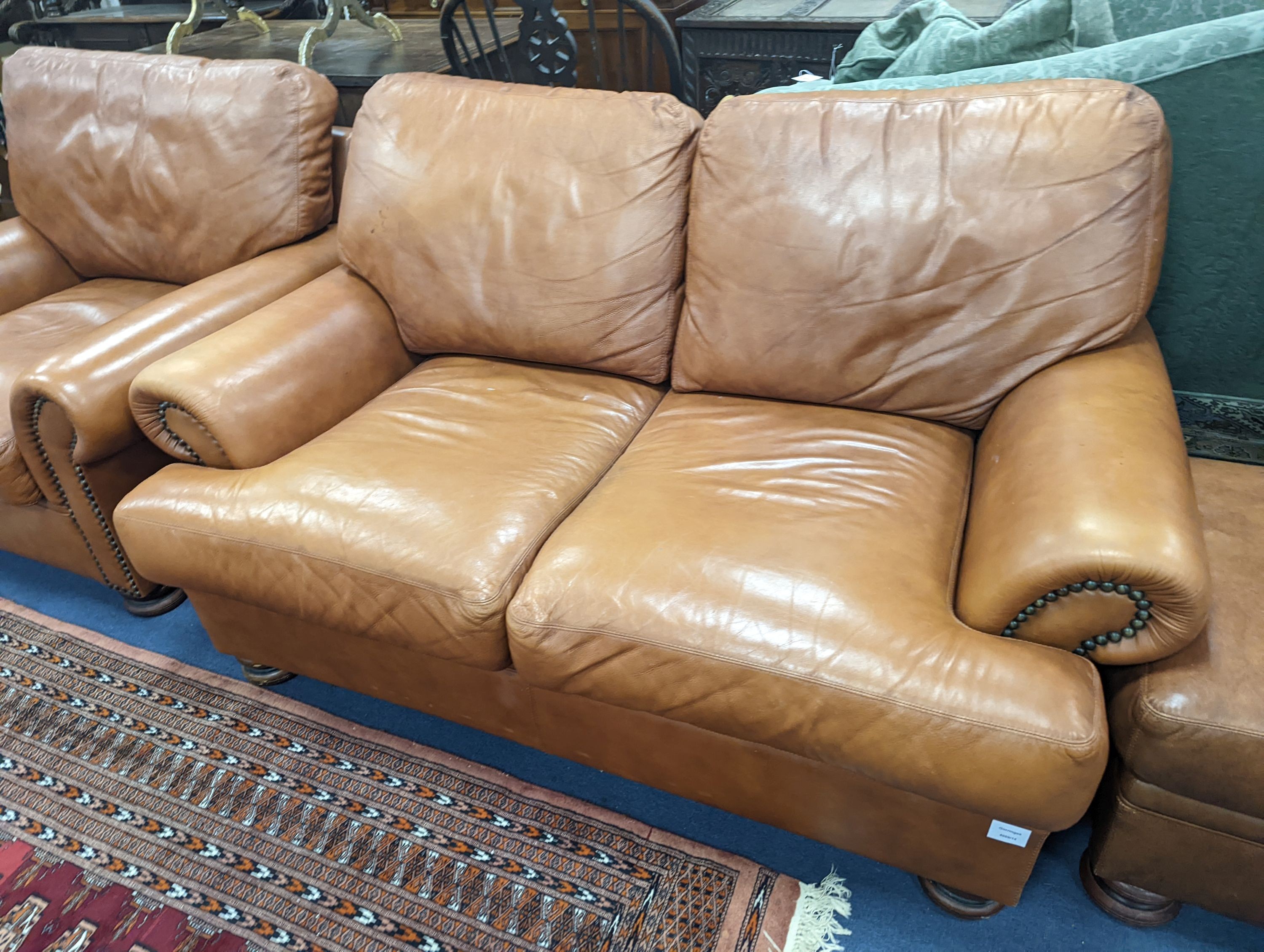 A contemporary tan leather three piece suite and footstool, settee length 150cm, depth 90cm, height 84cm